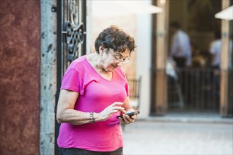 Older woman using cell phone in city