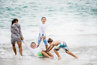 Family playing together in waves on beach
