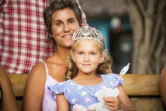 Mother holding daughter with wand and tiara