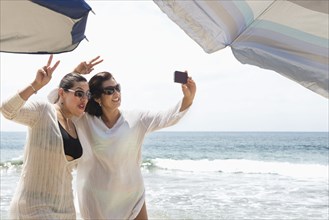 Hispanic women taking cell phone selfie at beach