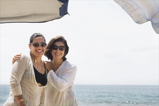 Hispanic women smiling together at beach