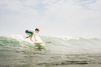 Mixed race boy surfing in waves