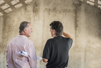 Caucasian architects talking near wall