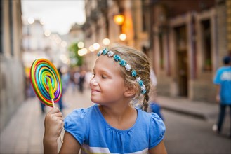 Smiling Caucasian girl enjoying lollipop in city