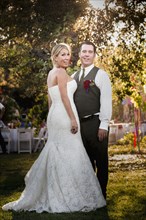 Caucasian bride and groom smiling at outdoor reception