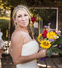 Smiling Caucasian bride holding bouquet of flowers