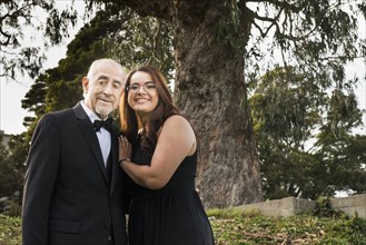 Hispanic grandfather and granddaughter smiling in formal wear