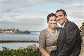 Hispanic couple in formal wear smiling near waterfront