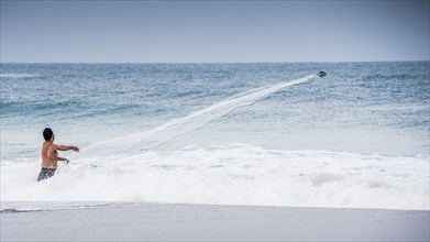 Man watching boat in ocean waves from beach