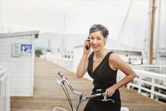 Older Caucasian woman talking on cell phone with bicycle