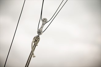 Close up of pulley and ropes under cloudy sky