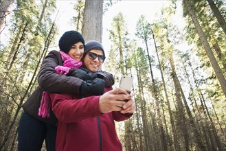 Hispanic teenage couple taking selfie in forest