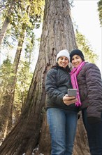 Hispanic mother and daughter taking selfie in forest