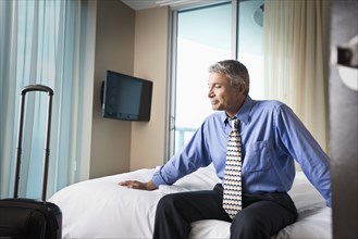 Caucasian businessman sitting on hotel bed