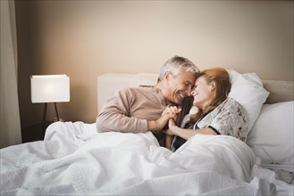 Smiling couple holding hands on bed