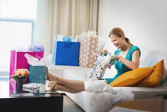 Woman opening shopping bags on sofa