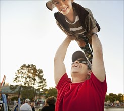 Father lifting son under blue sky