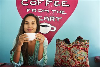 Hispanic woman drinking coffee in cafe