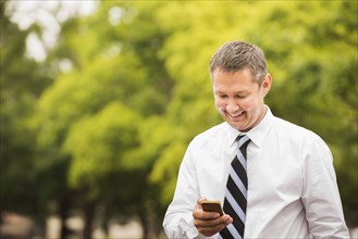 Caucasian businessman using cell phone outdoors