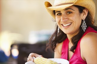Smiling Hispanic woman eating corn