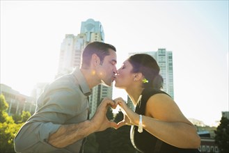 Hispanic couple kissing and making heart shape