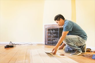 Hispanic man installing floors in new house