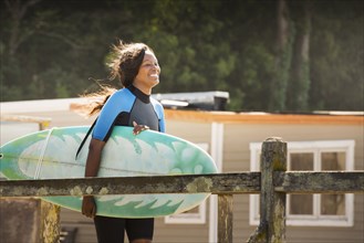 African American woman carrying surfboard outdoors
