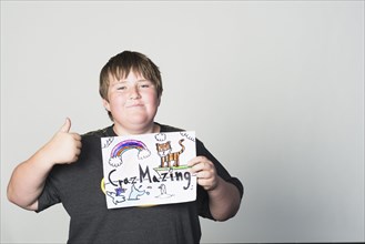 Boy holding sign gesturing thumbs-up