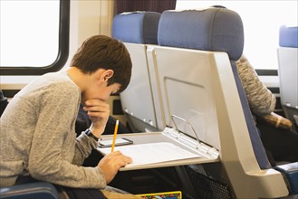 Mixed Race boy doing homework on train