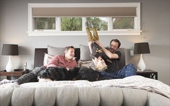 Caucasian fathers playing on bed with son and dog