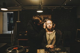 Caucasian dj holding headphones on woman