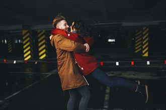 Caucasian couple hugging in parking garage