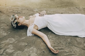 Caucasian bride laying on beach