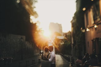 Caucasian couple hugging in city street at sunset