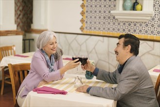 Older couple toasting with wine in restaurant