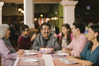 Family celebrating birthday or older man in restaurant