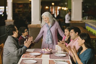 Family celebrating birthday of older woman in restaurant