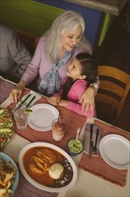 High angle view of grandmother hugging granddaughter in restaurant
