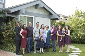 Multi-generation family posing near house