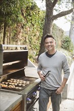 Portrait of smiling Chinese man cooking on grille