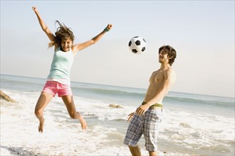 Couple playing with soccer ball on beach