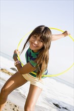 Woman playing with plastic hoop on beach