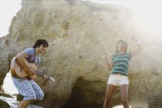 Man playing guitar for girlfriend on beach