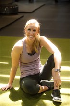 Smiling Caucasian woman resting on gymnasium floor