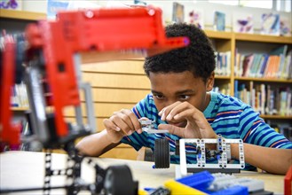 Boy assembling plastic blocks in library