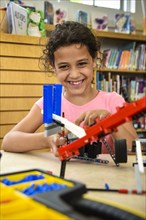 Girl assembling plastic blocks in library