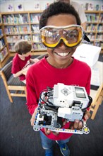 Boy wearing goggles posing with plastic blocks in library