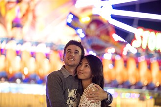 Smiling couple hugging in amusement park
