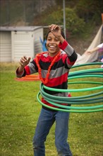 Black boy swinging multiple plastic hoops around waist