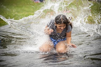 Water splashing on girl on outdoor plastic tarp